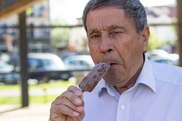 Modern and happy senior Man eating ice cream outdoor on a sunny day