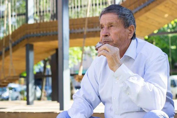 Modern and happy senior Man eating ice cream outdoor on a sunny day