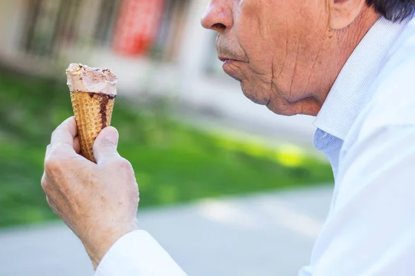 Modern and happy senior Man eating ice cream outdoor on a sunny day