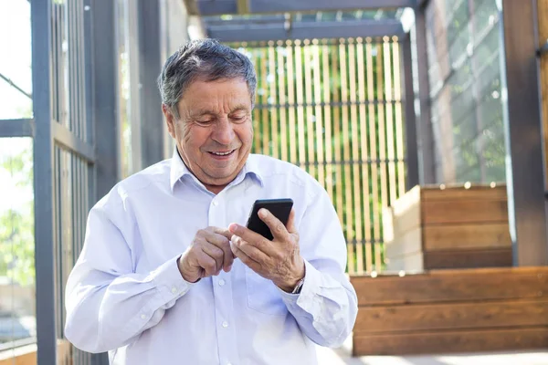 Senior man and his smartphone. Modern mature man have fun using smart phone outdoors