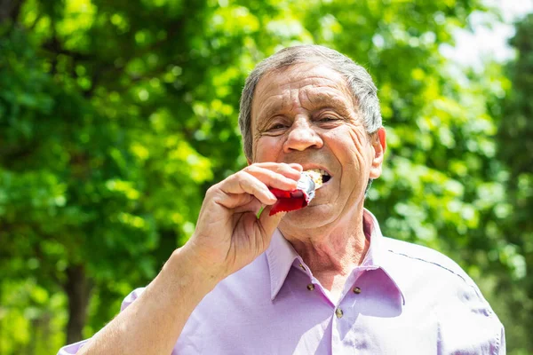 Senior man eating a protein bar, healthy lifestyle concepts, snack