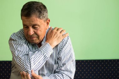 Sunbae, oturma odasında oturup omuz tutarak kas zedelenmesi geçiriyor.