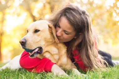 Parkta sevimli köpeğiyle gülümseyen genç bir kadın.