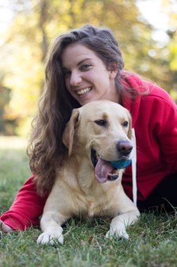 Parkta sevimli köpeğiyle gülümseyen genç bir kadın.