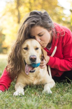 Parkta sevimli köpeğiyle gülümseyen genç bir kadın.