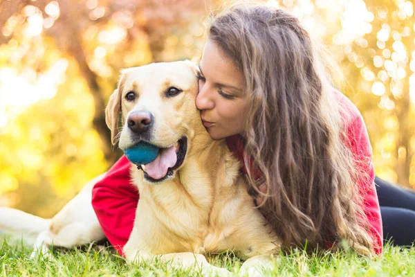 Parkta sevimli köpeğiyle gülümseyen genç bir kadın.