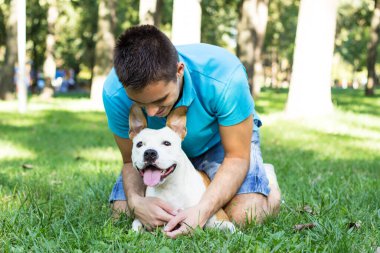 Halk parkında bir adam ve köpek sarılıyor.