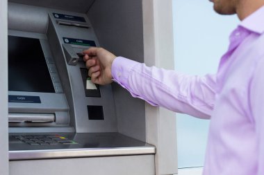 Genç işadamı bir para çekme makinesinden para çekiyor.