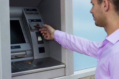 Genç işadamı bir para çekme makinesinden para çekiyor.