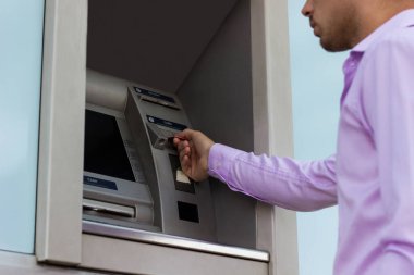 Genç işadamı bir para çekme makinesinden para çekiyor.