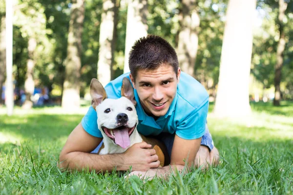 Halk parkında bir adam ve köpek sarılıyor.
