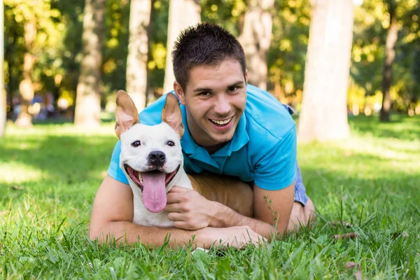 Halk parkında bir adam ve köpek sarılıyor.