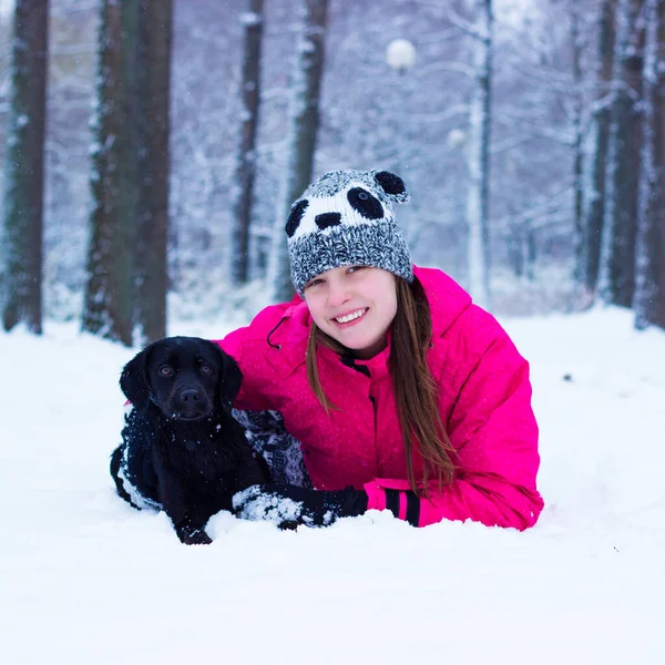 Tatlı kız köpeğine sarılıyor, kış vakti.