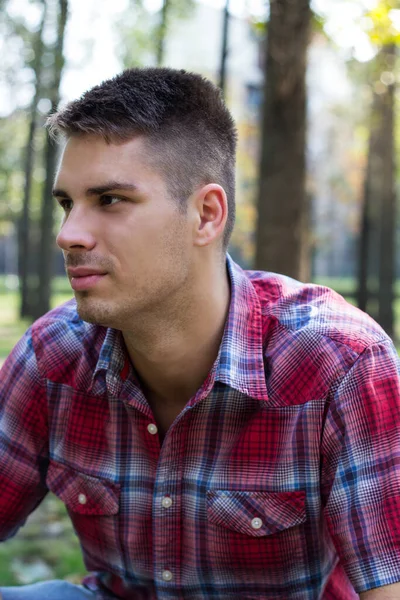 Parkta gülümseyen genç adam portresi