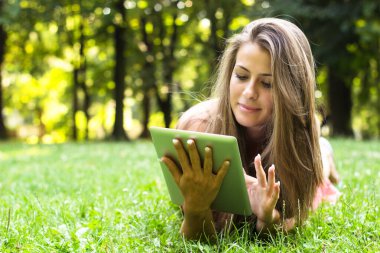 Doğada dijital tablet kullanan güzel genç bir kadın.