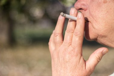 Kıdemli sigara içen kadın filtre ucu içiyor.