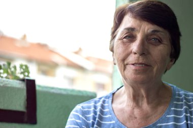 Kameraya bakan gülümseyen yaşlı bir kadının portresi.