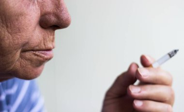 Kıdemli kadın oturuyor ve sigara içiyor.