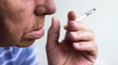 Kıdemli kadın oturuyor ve sigara içiyor.