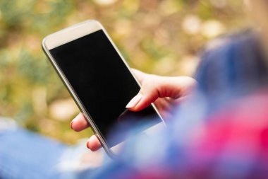 Young woman using smartphone in the public park
