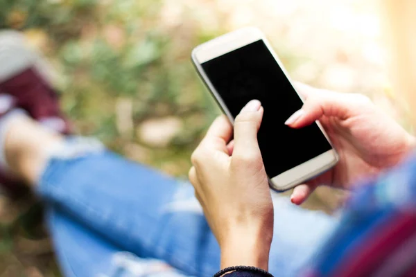 Parkta akıllı telefon kullanan genç bir kadın.