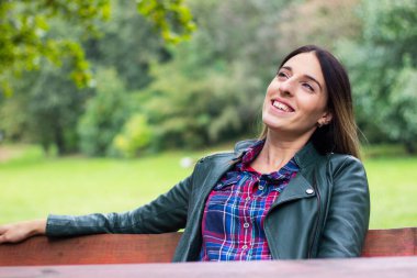 Beautiful carefree woman in autumn nature park. Smiling woman looking at camera at park during autumn
