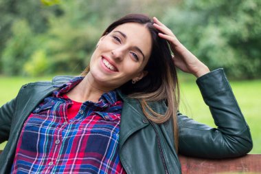 Beautiful carefree woman in autumn nature park. Smiling woman looking at camera at park during autumn