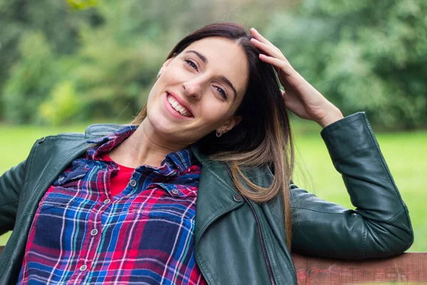 Sonbahar doğa parkında tasasız güzel bir kadın. Gülümseyen kadın sonbaharda parkta kameraya bakıyor.
