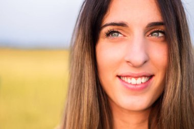 Portrait of beautiful woman in meadow, looking at camera