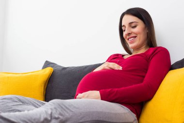 Hamile güzel bir kadın evde karnının üstünde el ele tutuşuyor. Huzurevinde dinleniyor.