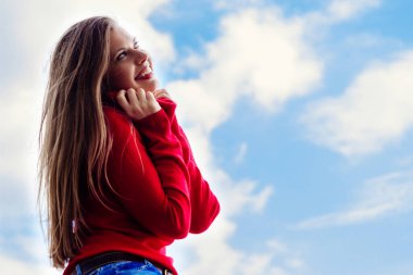 Beautiful smiling young girl, against a sky background