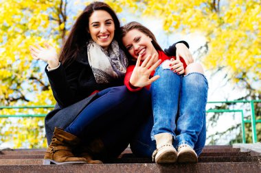 Two young smiling friends sitting on the stairs, autumn