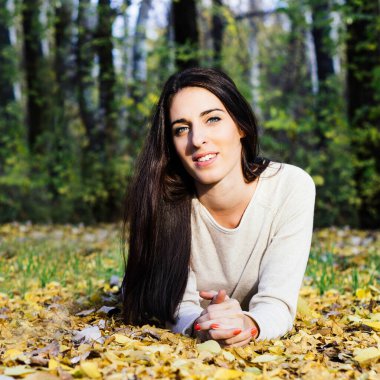 Portrait of a smiling girl who was lying on leaves, autumn