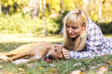 Happy young adult woman enjoys time at a park with her dog
