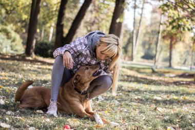 Happy young adult woman enjoys time at a park with her dog