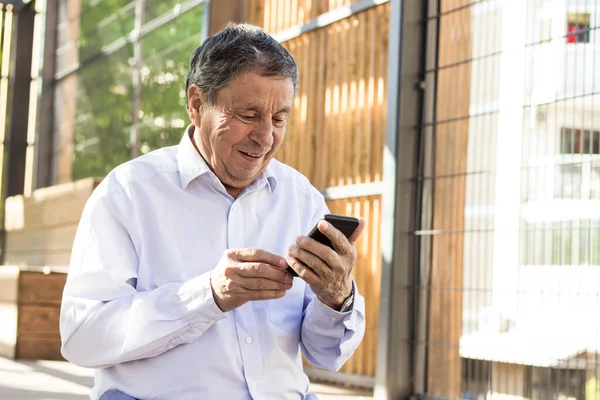 Senior man and his smartphone. Modern mature man have fun using smart phone outdoors