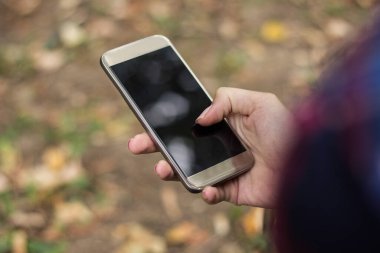 Açık havada akıllı telefon kullanan tanınmayan bir kadının yakın çekimi.