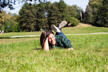 Gülümseyen genç kadın çimlere uzandı.