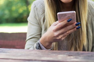 İnternette sörf yapmak. Açık havada akıllı telefon kullanan tanınmayan bir kadının yakın çekimi.