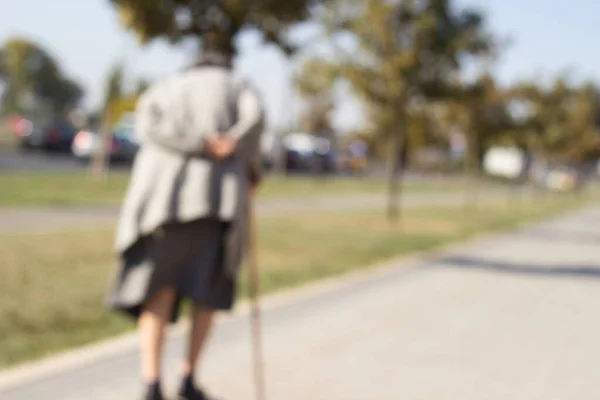 Grandmother walks down the street with a cane