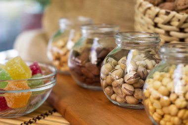 Sağlıklı yağ, protein yiyeceği ve atıştırmalık. Şam fıstığı, fındık, çam fıstığı, badem, balkabağı çekirdeği, ayçekirdeği, fıstık, kaju ve ceviz gibi fındık çeşitleriyle dolu Rustik ahşap masa.