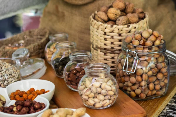 Nuts healthy fat and protein food and snack. Rustic wood table filled with a large assortment of nuts like pistachios, hazelnut, pine nut, almonds, pumpkin seeds, sunflower seeds, peanuts, cashew and walnuts