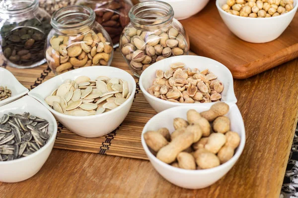 Nuts healthy fat and protein food and snack. Rustic wood table filled with a large assortment of nuts like pistachios, hazelnut, pine nut, almonds, pumpkin seeds, sunflower seeds, peanuts, cashew and walnuts