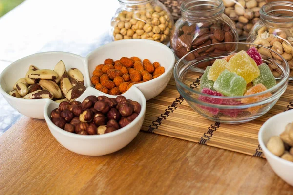 Nuts healthy fat and protein food and snack. Rustic wood table filled with a large assortment of nuts like pistachios, hazelnut, pine nut, almonds, pumpkin seeds, sunflower seeds, peanuts, cashew and walnuts