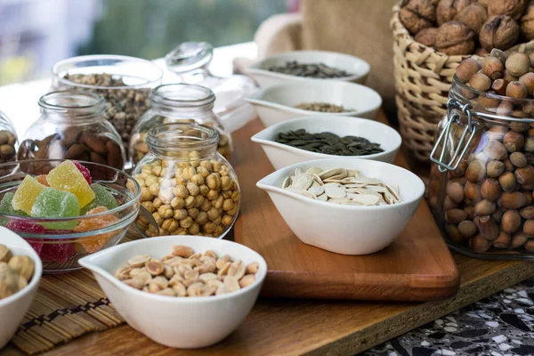 Nuts healthy fat and protein food and snack. Rustic wood table filled with a large assortment of nuts like pistachios, hazelnut, pine nut, almonds, pumpkin seeds, sunflower seeds, peanuts, cashew and walnuts