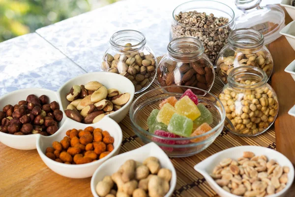 Nuts healthy fat and protein food and snack. Rustic wood table filled with a large assortment of nuts like pistachios, hazelnut, pine nut, almonds, pumpkin seeds, sunflower seeds, peanuts, cashew and walnuts