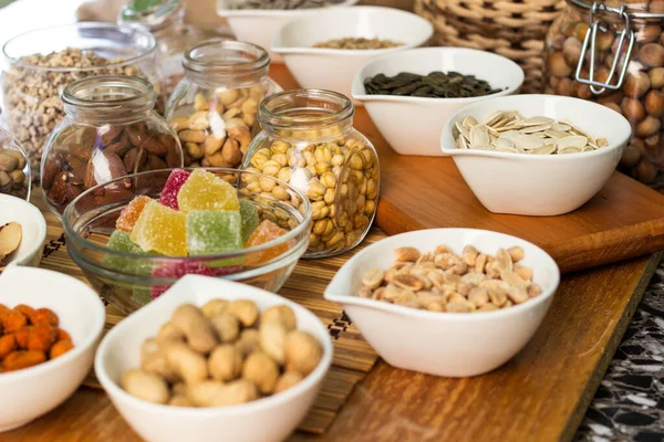 Nuts healthy fat and protein food and snack. Rustic wood table filled with a large assortment of nuts like pistachios, hazelnut, pine nut, almonds, pumpkin seeds, sunflower seeds, peanuts, cashew and walnuts