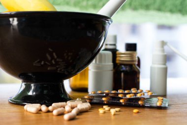 Geniş bir hap grubu, su toplayan paketler ve ilaç şişesi. Havan topu ve tokmak