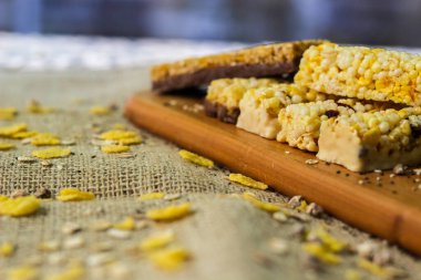 Tahta bir tahtanın üzerinde kurumuş meyve, fındık, çikolata ve mısır gevreği olan bir bar.