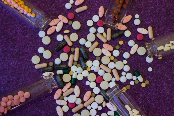 薬瓶や薬の錠剤が紫色の背景にこぼれて — ストック写真